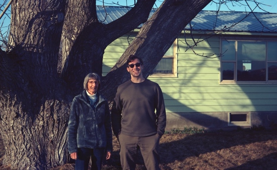Two people standing in front of a tree.