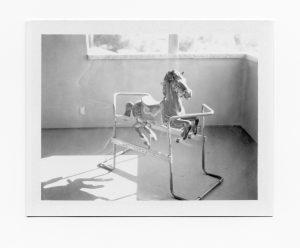A black and white FP-100B polaroid picture of an old rocking horse toy for children.