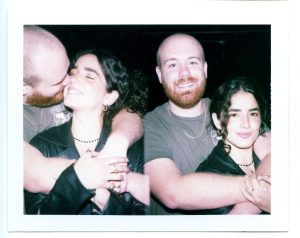 A Pack film Polaroid on FP-100C of Two photos side by side of a couple posing for the camera. The man has his arms around the womans shoulders and is hugging her from behind.
