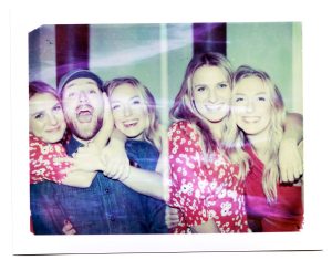 Two polaroids side by side with multiple people enthusiastically smiling for the camera.