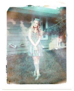 A polaroid of a woman posing in a yard.