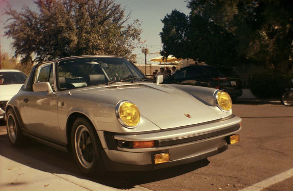 A film photo on expired film of a silver Porsche outside a Coffee shop in Scottsdale, AZ.